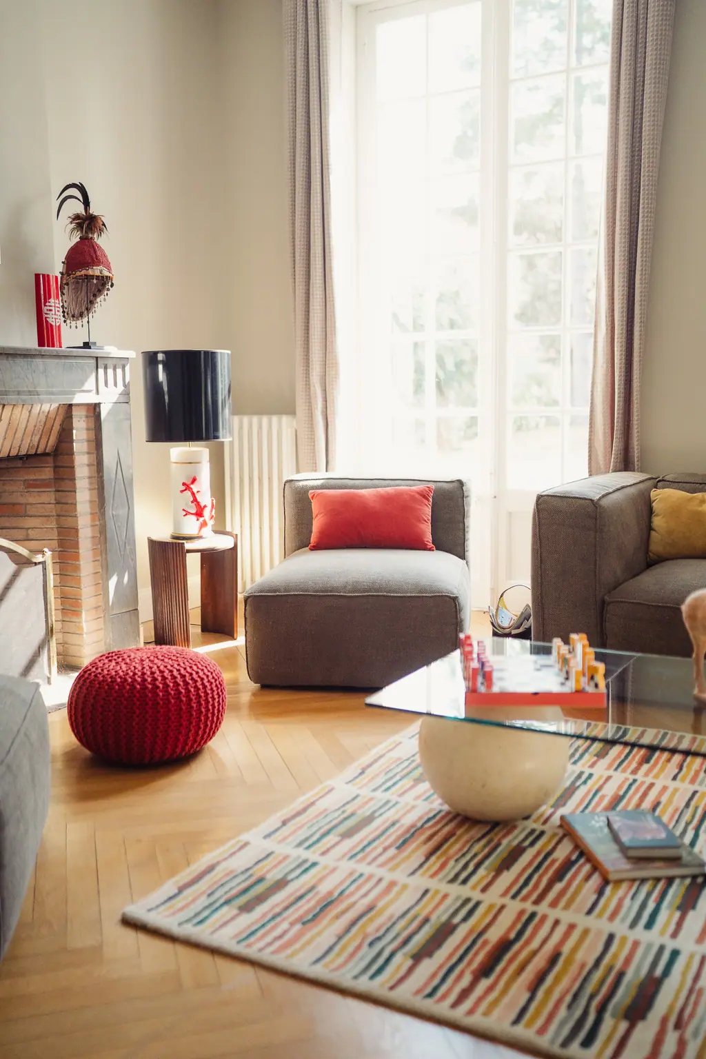 Le salon, sa cheminée, ses coussins rouges et son tapis rayé