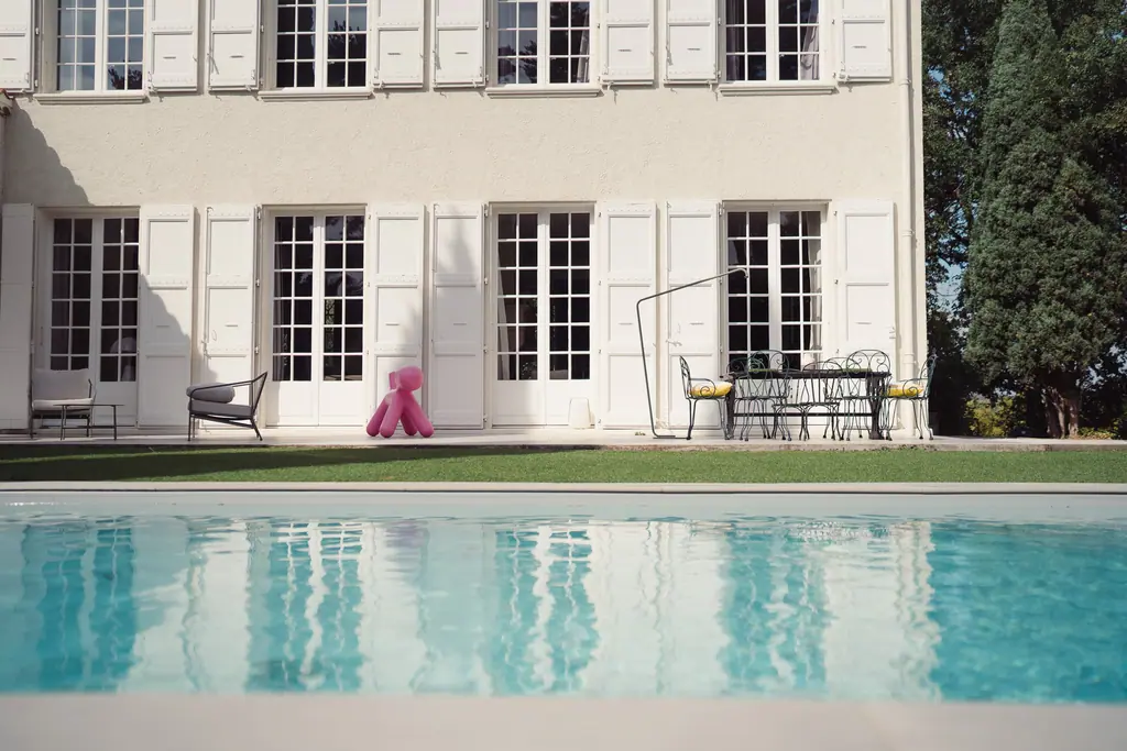 La piscine, où se reflètent la façade blanche et ses volets