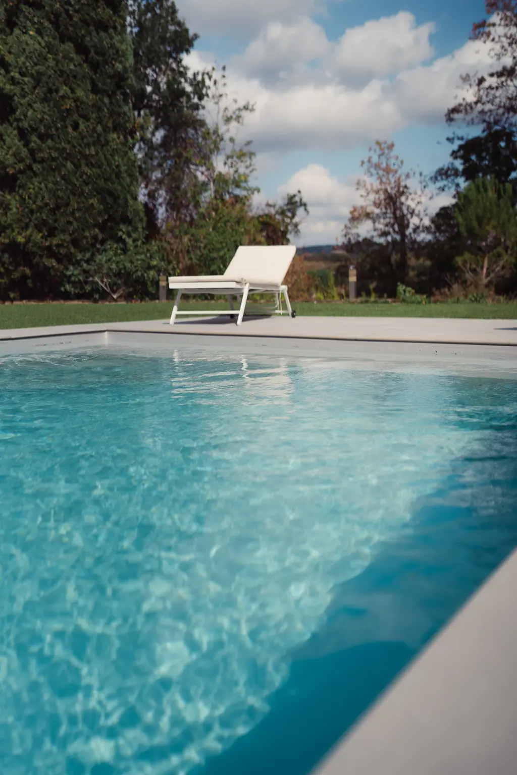 L'eau turquoise de la piscine et un transat blanc
