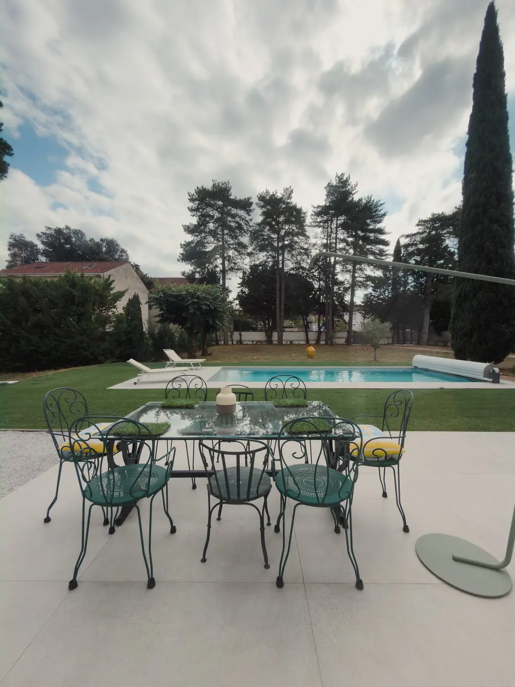 La table de jardin en fer forgé sur la terrasse, devant la piscine